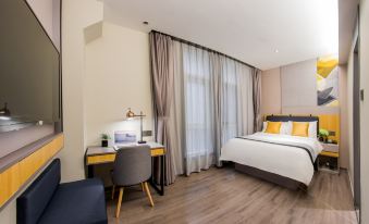 The bedroom features a double bed, a desk in the middle, and a large window that offers a breathtaking view of the city skyline at Home Inn Selected (Shanghai Wuning Road Metro Station Anyuan Road)
