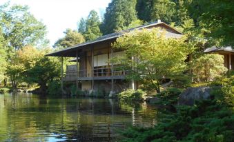 a wooden house situated on the edge of a lake , surrounded by trees and greenery at Toyoko Inn Shizuoka Fujieda Eki Kita Guchi