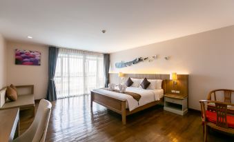 a spacious bedroom with hardwood floors , a large bed , and a door leading to a balcony at Grand Ratchapruek Hotel