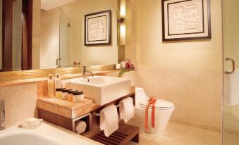 a modern bathroom with a bathtub , sink , and toilet , along with framed pictures on the wall at Oakwood Premier Cozmo Jakarta