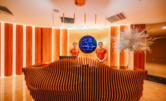 a hotel lobby with two women standing in front of a reception desk , both wearing orange shirts at Seashells Phu Quoc Hotel & Spa