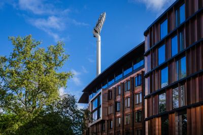 a modern building with a tall metal pole in front of it , surrounded by trees at Oval Hotel at Adelaide Oval, an EVT hotel