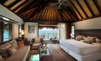 a luxurious hotel room with a large bed , wooden floors , and a view of the ocean at Hilton Moorea Lagoon Resort and Spa