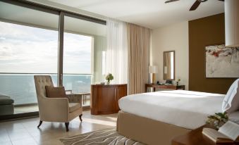 a large bedroom with a king - sized bed , a dresser , and a window overlooking the ocean at Jumeirah Port Soller Hotel and Spa