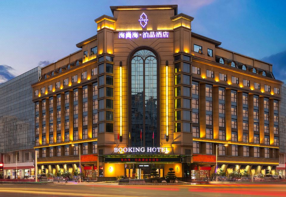 "the hotel booking hotel is illuminated by lights and has a large sign that says "" booking hotel ""." at Mianyang Booking Hotel