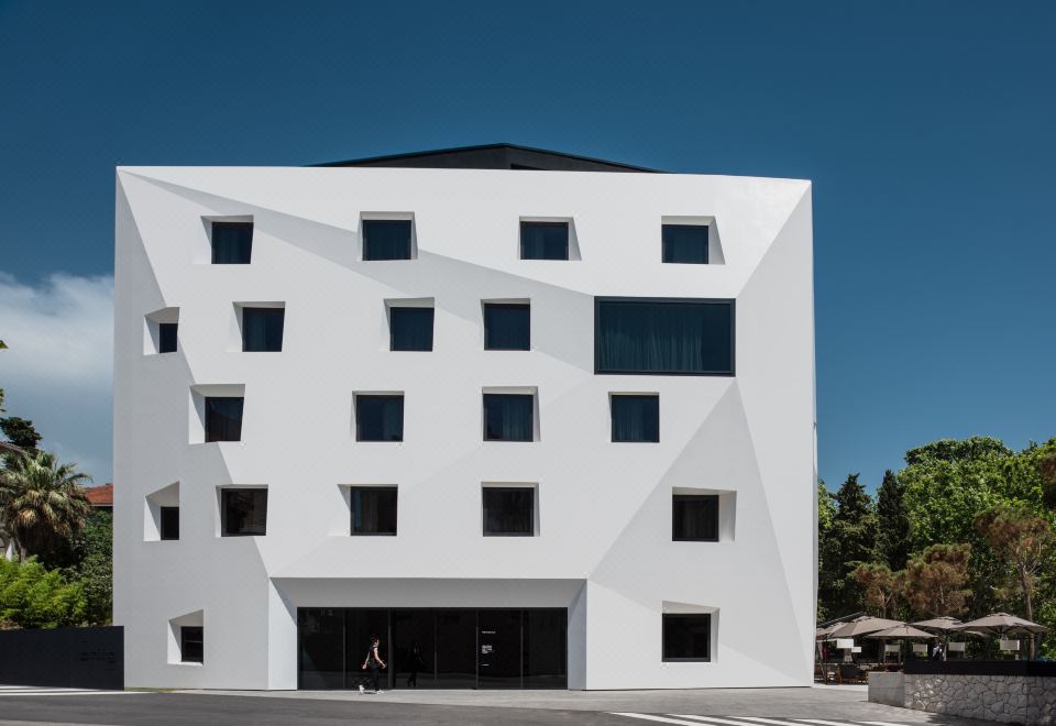 a modern white building with a triangular roof and large windows , located in a parking lot at Briig Boutique Hotel