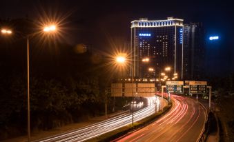 a busy city street at night , with multiple cars and a truck driving on the road at Wellington Hotel