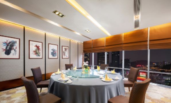 A room with large windows and an oval table set for four people in the dining area at Jianguo Hotel, Guangzhou