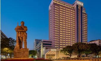 a large , modern building with a statue in front of it and a man standing next to it at Guangzhou Hotel