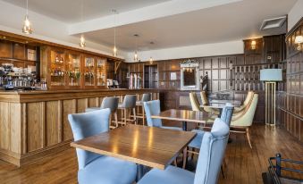 a room with wooden furniture and blue chairs , a bar area with bottles on the counter at Thurnham Hall