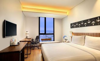 a hotel room with a large bed , desk , and window , providing a comfortable and modern atmosphere at BATIQA Hotel Lampung