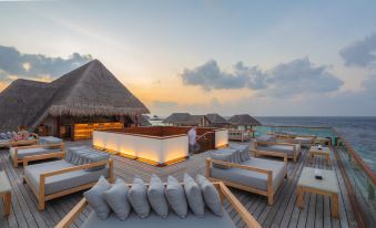 a rooftop terrace with comfortable seating , umbrellas , and a large pool , overlooking the ocean at sunset at Heritance Aarah-Premium All Inclusive