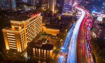 At night, a cityscape is adorned with illuminated buildings and a prominent clock at Yan An Hotel