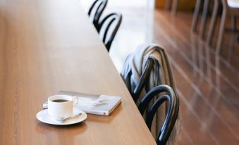 a wooden table with a cup of coffee and a book placed on it , surrounded by chairs at Mitsui Garden Hotel Okayama