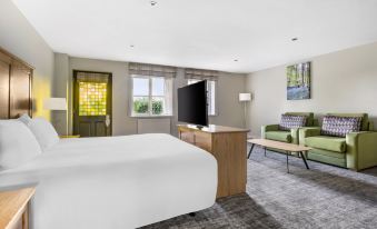 a modern hotel room with a white bed , wooden furniture , and a flat - screen tv at Thurnham Hall