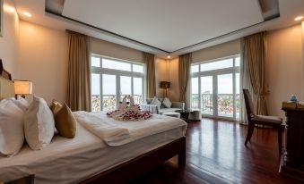 a luxurious bedroom with wooden flooring , white beddings , and large windows offering views of the ocean at Lbn Asian Hotel