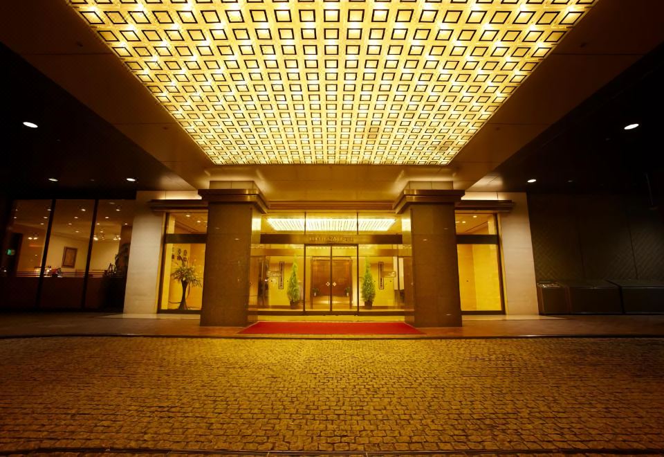 a large , dimly lit entrance with a red carpet leading to a building with an open door at Keio Plaza Hotel Hachioji