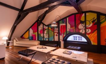 a room with a wooden floor and a unique geometric design on the wall , featuring two black leather couches , a coffee table , and at L'Hotel de Beaune