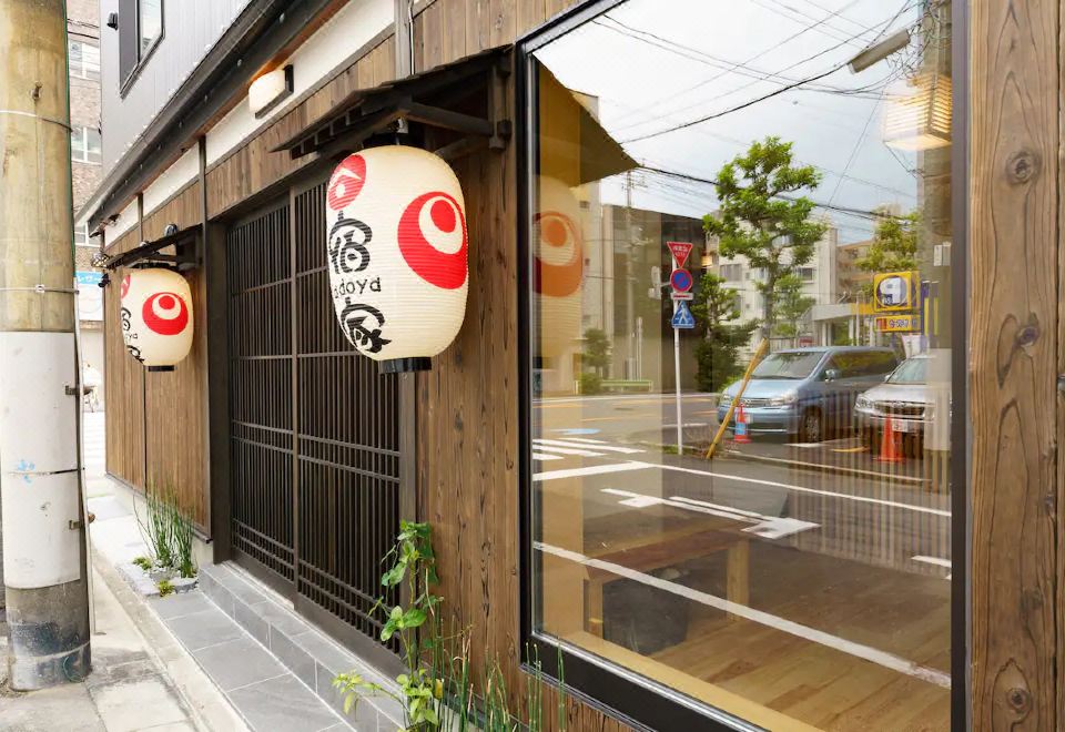 A restaurant with wooden floors and large windows offers outdoor seating on the side at Yadoya Fukurou