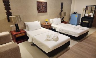 a hotel room with two beds , a nightstand between them , and decorative items on the wall at Kim Hotel at Bangplong