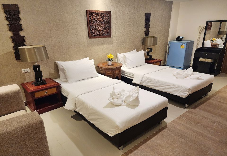 a hotel room with two beds , a nightstand between them , and decorative items on the wall at Kim Hotel at Bangplong