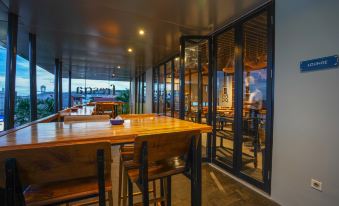 a wooden dining table surrounded by chairs in a restaurant setting , with a view of the ocean at BATIQA Hotel Lampung