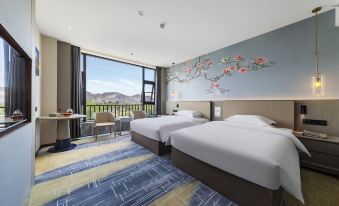 a hotel room with two beds , a desk , and a window overlooking a beautiful mountain view at Tibet Hotel