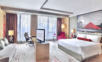 A modern bedroom is furnished with large windows, a bed, and a desk in the middle at Sofitel Guangzhou Sunrich