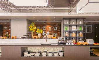 a modern coffee shop with a long wooden counter and various pots and pans on display at M Hotel