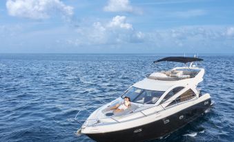 a woman is standing on the deck of a luxury yacht , enjoying the view of the ocean at Naladhu Private Island Maldives