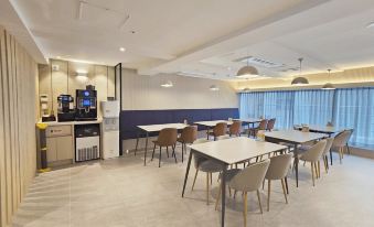 a modern dining area with several tables and chairs , along with a coffee maker on the counter at Hotel Foret Premier Nampo
