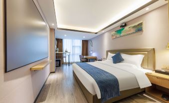 In the middle room, there is a large bed with an attached sitting area and a table for two at Hejing Hotel (Futian Exhibition Center, Shenzhen)