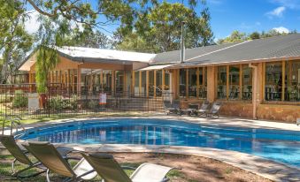 a backyard with a swimming pool surrounded by lounge chairs and a house , providing a relaxing atmosphere at Wilpena Pound Resort