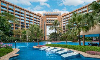 a large swimming pool with a fountain in the center and palm trees surrounding it at Royal Garden Hotel