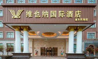 The front entrance of a hotel is adorned with an oriental sign, while another building stands nearby at Vienna International Hotel (Shanghai Pudong Airport)