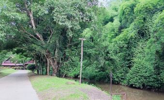 a park with a river running through it , surrounded by lush green trees and grass at Lanna Resort Chiang Mai