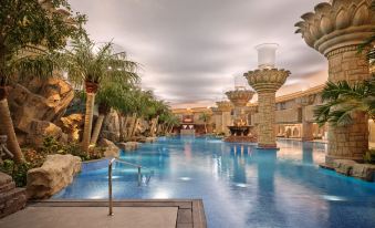 There is a large pool surrounded by trees and an indoor swimming area adjacent to it at Grand Hyatt Beijing