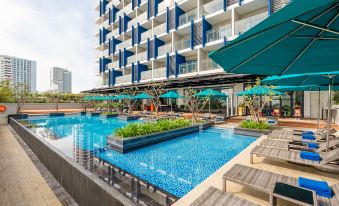a large swimming pool is surrounded by lounge chairs and umbrellas in front of a modern building at TUI BLUE Nha Trang