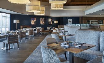 a dining room with several tables and chairs arranged for a group of people to enjoy a meal together at Delta Hotels Waltham Abbey