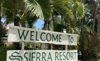 "a wooden sign that reads "" welcome to sierra resort "" is surrounded by palm trees and greenery" at Sierra Resort