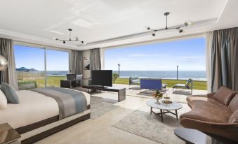 a modern bedroom with a large bed , television , and sliding glass doors leading to a balcony overlooking the ocean at Pickalbatros White Beach Taghazout - Adults Friendly 16 Years Plus - Ultra All Inclusive
