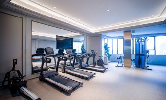 In the middle of a large room, there are several exercise machines and an indoor treadmill at Mercure Guangzhou Beijing Road Pedestrian Street Hotel