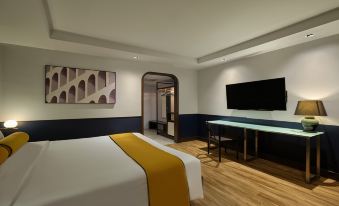 A modern bedroom features a double bed, a desk in the middle, and a large screen at Graph Hotels