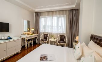 a modern hotel room with white walls , wooden floors , and large windows , featuring a bed , two armchairs , a table , and two at Alagon Saigon Hotel & Spa