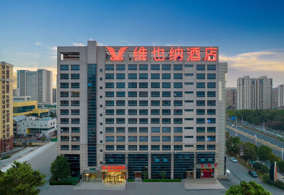 a large hotel building with a red and white sign on the side of it at Vienna Hotel