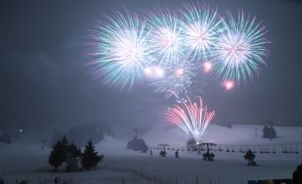 a snowy mountain with a ski lift in the background and colorful fireworks exploding in the sky at Naeba Prince Hotel