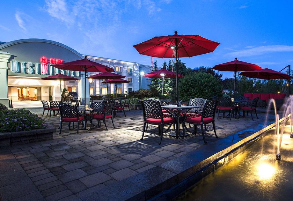 an outdoor dining area with red umbrellas , tables , and chairs set up for a meal at Westminster Hotel