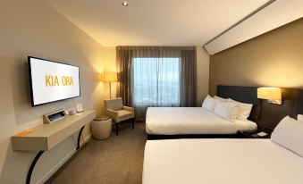 a hotel room with two beds , a desk , and a window , decorated in white and brown colors at Sudima Auckland Airport