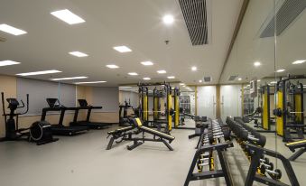 A spacious room with multiple exercise equipment, including an indoor weight machine in the center at Guangzhou Tianhe Taikoohui - Coffee Rupin Hotel