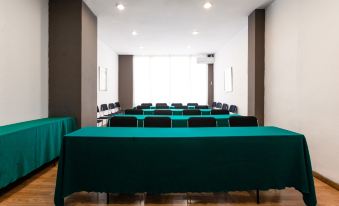 a large conference room with multiple rows of chairs arranged in a semicircle , and a table with a green cloth in the center at Catalonia Punta del Rey